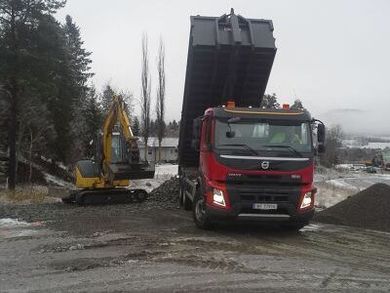 Lastebil dumper grus ved gravemaskin