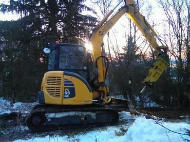 Gravemaskin i snødekt skog